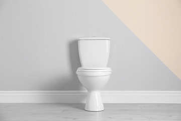 New toilet bowl near color wall indoors