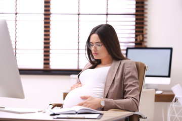 Young pregnant woman suffering from pain while working in office