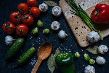 Fresh raw vegetables islated on black table background. Top view. Tomatoes, cucumber, green onion, garlic, pepper. Healthy vegetarian food concept