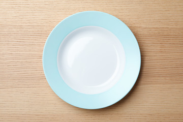 Stylish ceramic plate on wooden background, top view