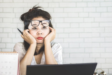 unmotivated Asian female worker feeling tired and sleepy at workplace 