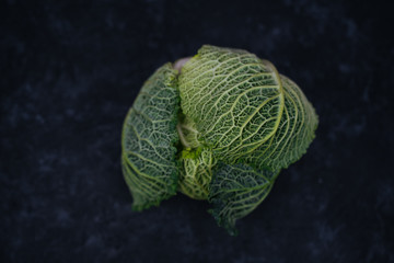 Obraz premium Fresh raw savoy cabbage isolated on black table background. Vegetarian food. Healthy vegetables