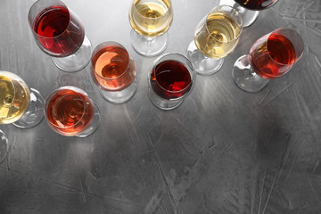 Different glasses with wine on grey background, flat lay. space for text
