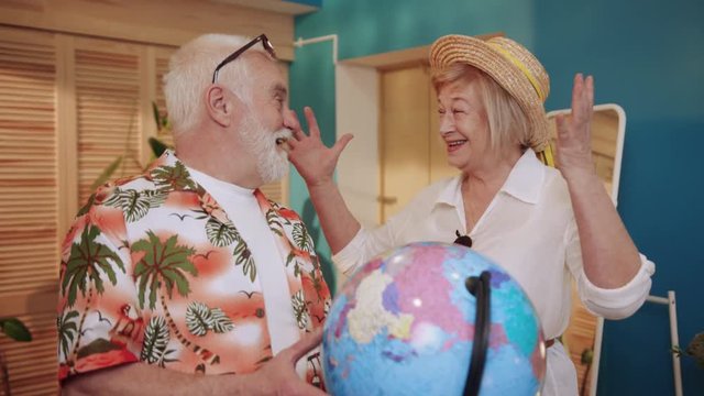 Close up senior couple looking hold globe talk going on holiday senior suitcase together caucasian holiday bag elderly family girl home mature older pensioner tourism travel trip slow motion