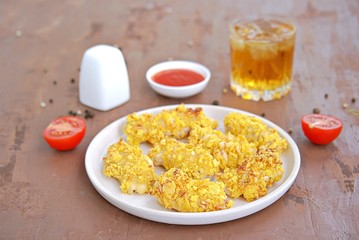 Crispy chicken strips in cornflakes and parmesan cheese on a white plate. Selective focus. American cuisine.
