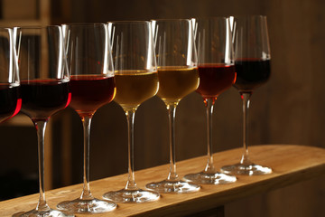 Glasses of different wines against blurred background. Expensive collection