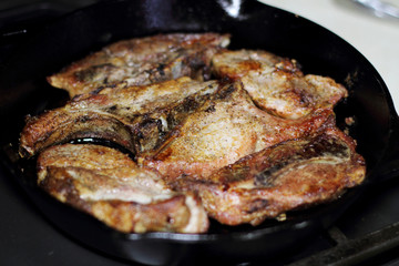 Country style cut pork ribs in a cast iron pan on the stove top.