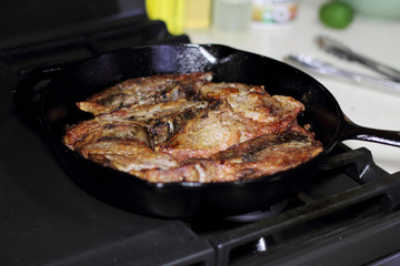 Country style cut pork ribs in a cast iron pan on the stove top.