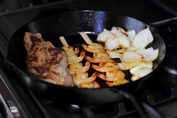 Surf and turf with NY strip and shrimp kabobs with grilled onions, in a cast iron skillet.