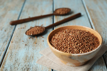 Uncooked buckwheat in bowl on table. Space for text