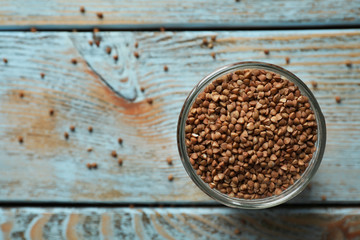 Uncooked buckwheat in glass on table, top view. Space for text