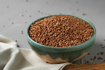 Uncooked buckwheat in ceramic bowl on table