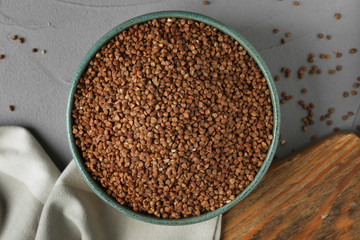 Uncooked buckwheat in bowl on table, flat lay