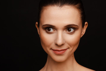 Portrait of a beautiful woman with collected hair and bare shoulders on a black background