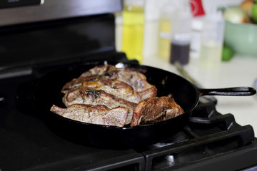 Country style cut pork ribs in a cast iron pan on the stove top.