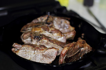 Country style cut pork ribs in a cast iron pan on the stove top.