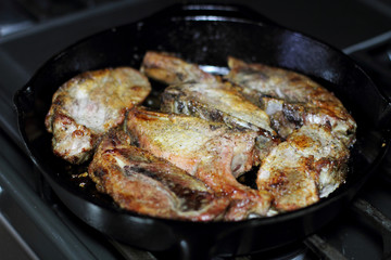 Country style cut pork ribs in a cast iron pan on the stove top.