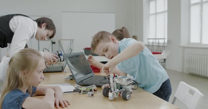 Curious kids working on a functional programable robot during robotics class at school. 4K UHD 60 FPS SLOW MOTION