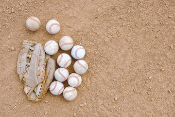 Fototapeta na wymiar Old used baseballs with leather glove on field with copy space for sports concept.