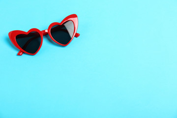 Red heart shaped sunglasses on color background, top view. Space for text