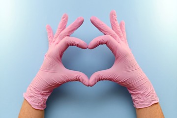 The heart, figure built from the hands in pink rubber medical gloves on a blue background.