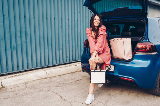 a young girl dressed and dressed sexy that comes from shooping with the packs in hand with a blue car