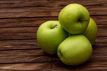 Green apples on dark brown wooden background. Summer fruits. Natural vitamins. Healthy food.