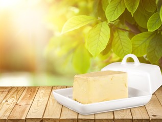 Pat of fresh farm butter on a butter dish with a knife on backgrouund