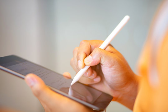 Hand Holding Stylus Pen Writing Down On Tablet