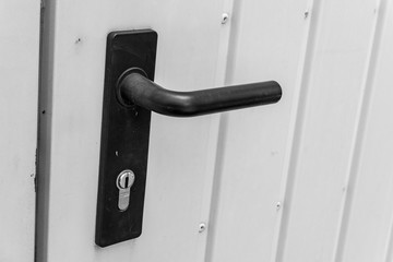 black door handle with lock at a door to the garage made of sheet metal