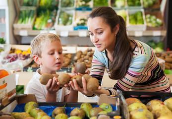 Fototapeta premium mother with little boy buying kiwi at store