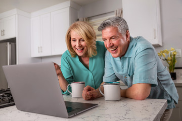 Grandparents on computer communicating with grandkids via video chat from home kitchen