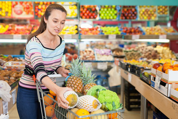 Obraz premium Positive Caucasian female choosing fresh fruits at shop