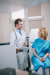 Obraz premium selective focus of handsome doctor holding digital tablet near happy patient sitting in armchair