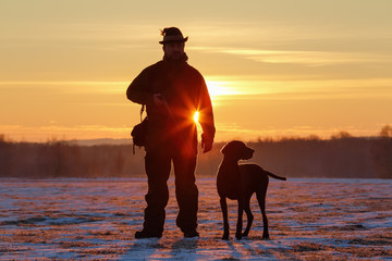 A hunter in the hat with a gun and his German Shorthaired Pointer dog breed friend. Beautiful...