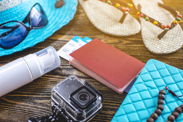 Travel holiday supplies: hat, sunglasses, flip flops, passport and airline tickets on old wooden background. Flat lay