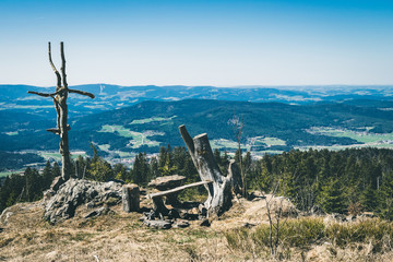 View from the top of a mountain into the valley with clouds in the blue sky and beautiful green trees and lots of rocks