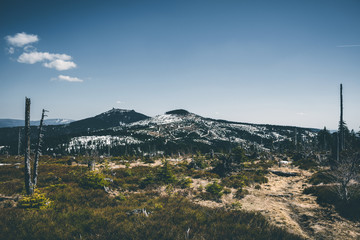 View from the top of a mountain into the valley with clouds in the blue sky and beautiful green trees and lots of rocks