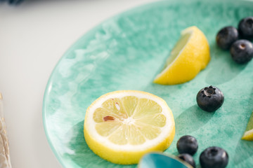 Fototapeta na wymiar Close-Up of Blueberries and Lemon Slices on Teal Plate