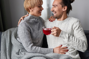 Happy couple drinking red tea on couch