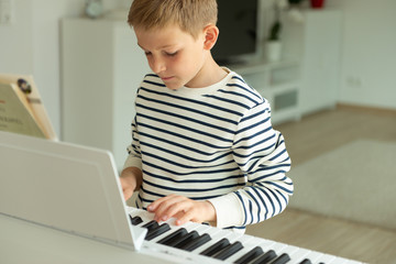 Fototapeta na wymiar Teenager boy has training course with e-piano at home