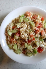 Bulgur wheat, tomato, cucumber and feta cheese salad. Top view.