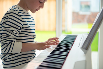 Teenager boy has training course with e-piano at home