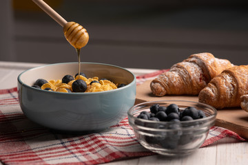 Croissants, corn flakes and berries with honey on table. Healthy breakfast concept. Sweet delicious dessert. Diet lunch