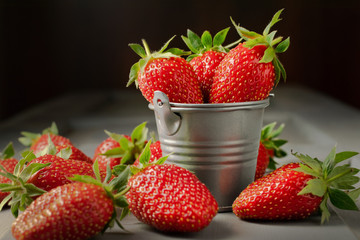 Strawberries on the table and in a metal decorative bucket