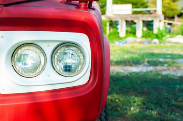 Close up classic red truck double headlight with white frame and  green yard,