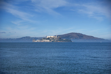 SAN FRANCISCO, CALIFORNIA, UNITED STATES - NOV 25th, 2018: Alcatraz prison in fog panorama during a sunny day in November as seen from pier 39