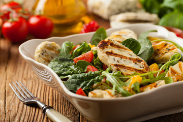 Traditional Greek salad with grilled Halloumi cheese with basil. Front view.