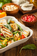 Traditional Greek salad with grilled Halloumi cheese with basil. Front view.