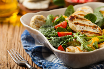 Traditional Greek salad with grilled Halloumi cheese with basil. Front view.